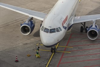Worker attaching brake pads to a parked aircraft