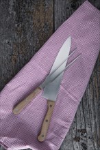 Carving knife and fork with a kitchen towel on rustic wooden boards