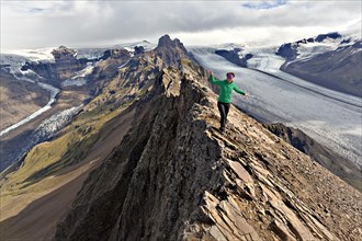 Mountaineer on the summit ridge in front of a glacier tongue