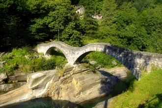 Stone bridge across rocky alpine foothills stream in the remote valley of Val Verzasca