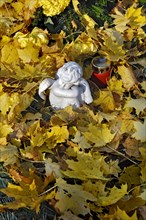 Putto and votive candle with autumn leaves on the Ostfriedhof or East Cemetery