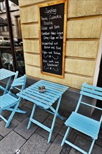 Street cafe with a menu board and blue tables and chairs