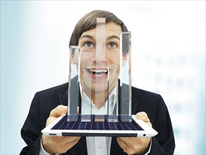 Happy businessman holding an iPad with a glassy bar chart