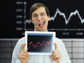 Winking businessman holding an iPad with a rising stock chart