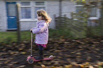 Four-year-old girl having fun riding a scooter