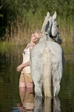 Woman standing in water with a Hanoverian horse