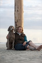 Woman with a Weimaraner on the beach