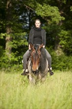 Woman riding a Belgian Draft horse in a meadow