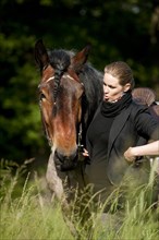 Woman with a Belgian Draft Horse in a meadow