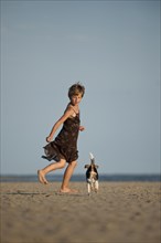Girl running with a Dansk-Svensk Gardshund or Danish-Swedish Farmdog along the beach