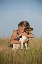Girl sitting with a Dansk-Svensk Gardshund or Danish Swedish Farmdog in a meadow