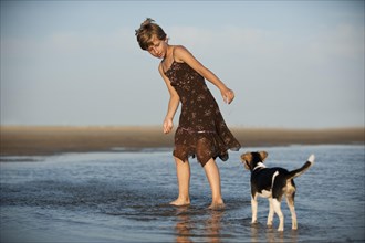Girl playing with a Dansk-Svensk Gardshund or Danish-Swedish Farmdog on the beach