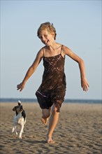 Girl running with a Dansk-Svensk Gardshund or Danish-Swedish Farmdog on the beach