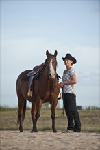 Woman standing next to a Quarter Horse