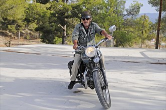Elderly man riding a Triumph Tiger 500cc motorbike