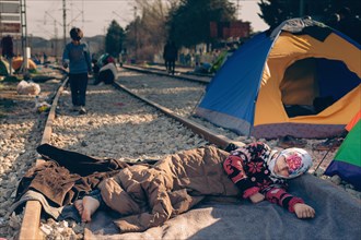 Young woman sleeping between train tracks in refugee camp of Idomeni at Greek-Macedonian border