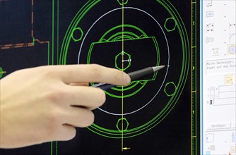 Hand pointing to a technical drawing on a monitor