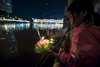 Young girl placing a ceremonial raft in the river