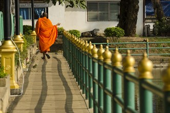 Buddhist monk walking across a bridge