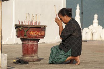 Woman in prayer holding incense sticks