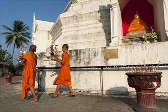 Young Buddhist monks with offerings in front of a Pagoda or Chedi