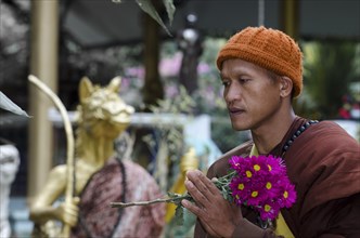 Buddhist monk holding flowers during a morning alms collection