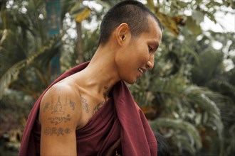 Smiling Buddhist monk with tattoos collecting alms in the morning