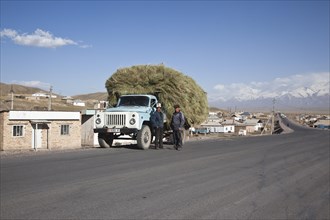 Kyrgyz men standing next to a fully loaded truck