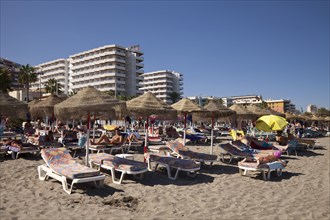 Sunbeds and sunshades on the beach in front of hotel buildings