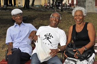 Three Cubans sitting on a park bench