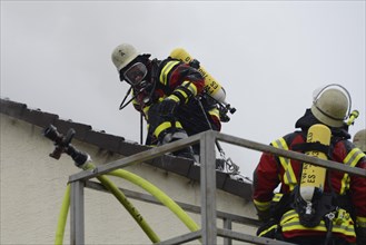 Firefighters wearing breathing equipment while extinguishing a roof fire