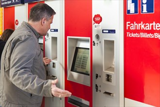 Confused man standing in front of a ticket machine