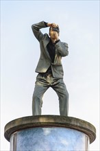 Sculpture of a man taking a photograph standing on an advertising column