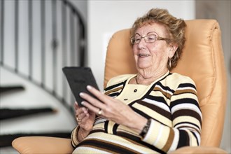 Smiling elderly woman reading an eBook