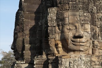 Large sculptures of heads on tower of Khmer temple
