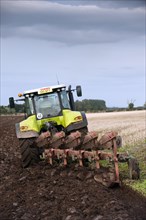 Claas 640 Axion tractor with five furrow reversible plough