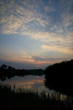 View of cirrocumulus clouds over flooded former gravel pit habitat at sunset