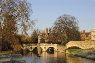 View of river with punt approaching bridge and college buildings in frost