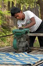 A young Khmer starting the engine of the bamboo train
