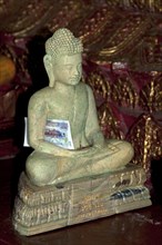 Buddha statue made of marble with a banknote as an offering inside the pagoda of the Buddhist temple of Wat Phnom