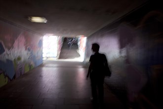A man walking in a dark tunnel with graffiti