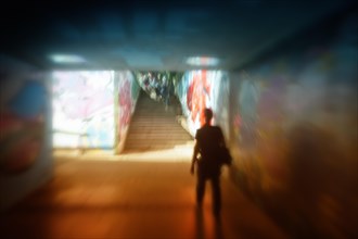 A man walking in a dark tunnel with graffiti