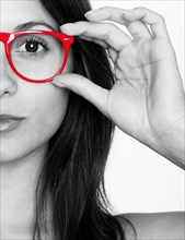 Half portrait of a young woman in black and white with red glasses
