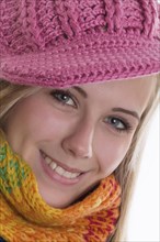 Smiling young woman wearing a colourful scarf and a pink knit cap