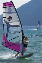 Female windsurfer surfing across the water on her board