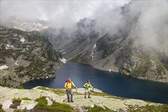 A man and a woman hiking at the Lago della Crosa mountain lake