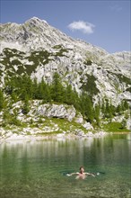 Man skinny dipping in the mountain lake of Veliko Jezero