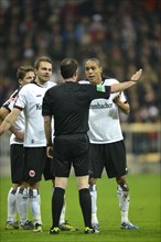 Players of Eintracht Frankfurt are discussing a decision with referee Marco Fritz