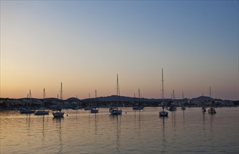 Sailing boats in a harbour at sunset