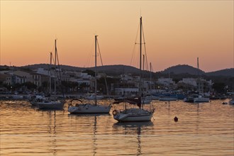 Sailing boats in a harbour at sunset